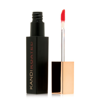 A black rectangular tube of matte lip color next to its rose gold cap and doe foot applicator. The color visible on the applicator and through the tube is Come Hither, a bright red-orange